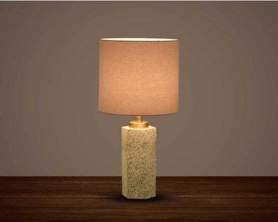 Table lamp in stone terrazzo with a metal base & translucent fabric shade in an earthy natural design.